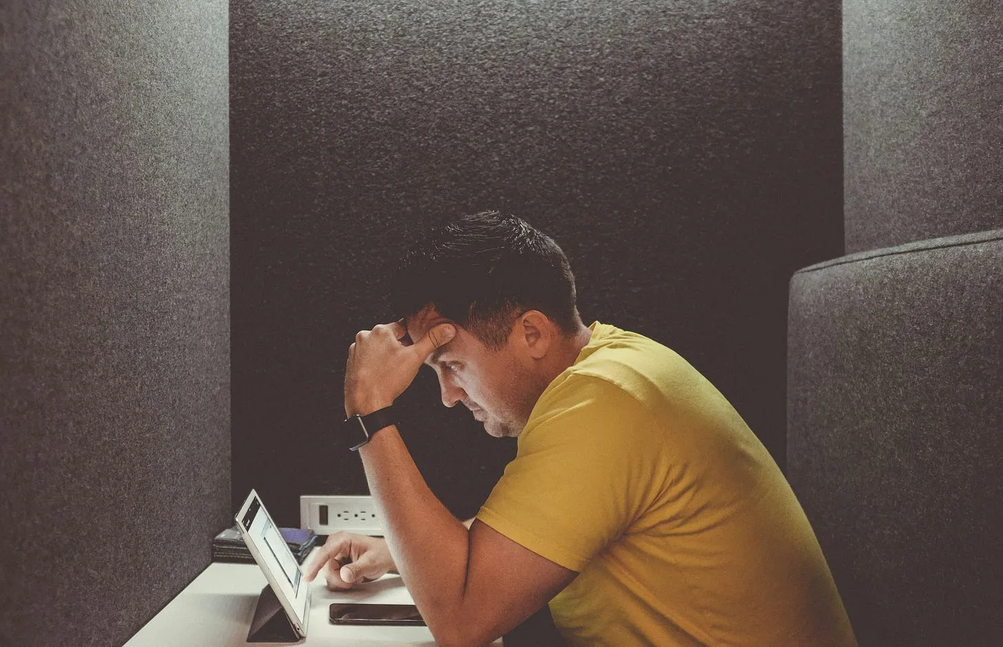 A developer sitting alone in a booth and looking at a laptop
