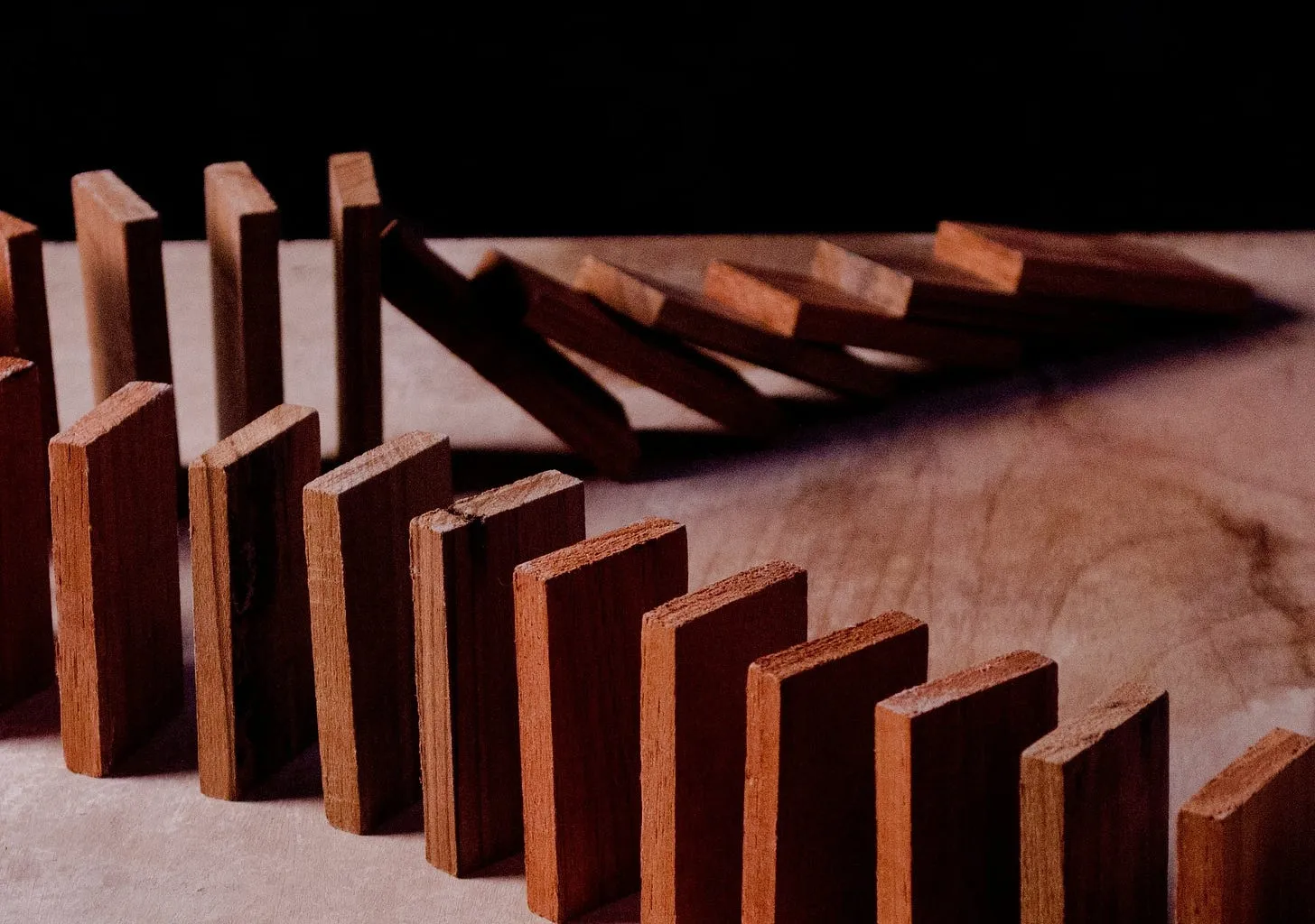 A line of wooden dominoes partway through collapsing